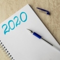 bialy-notatnik-i-niebieski-napis-2020-niebieski-dlugopis-na-papierze-i-czapka-na-stole_156396-19