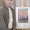 Paweł Kisiel na tle swojej nagrodzonej pracy na wystawie. 